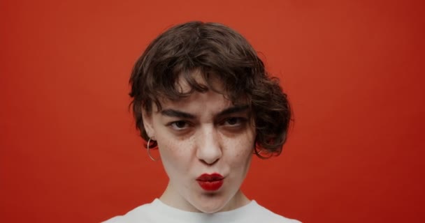 En brunett med röda läppstift grimaser, skildrar olika känslor — Stockvideo