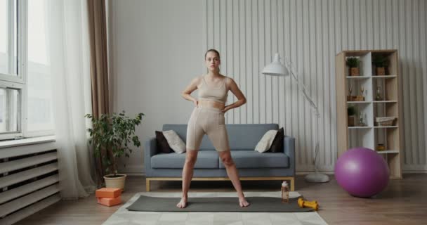 Spor kıyafetleri giymiş Avrupalı bir kız, kalçalarında ısınma turu yapıyor. — Stok video