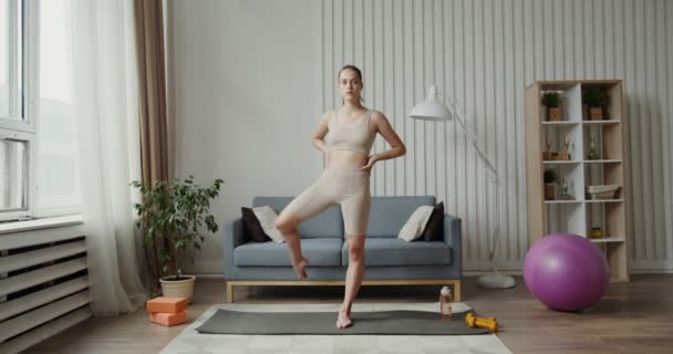 Europæisk pige klædt i sportstøj, laver en opvarmning rotation med benene – Stock-video