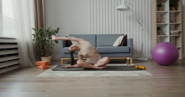 European girl dressed in sportswear makes bends in the lotus position — Stock Video