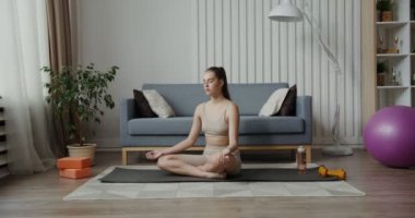 Spor giyimli Avrupalı kız gözleri kapalı lotus pozisyonunda oturuyor.