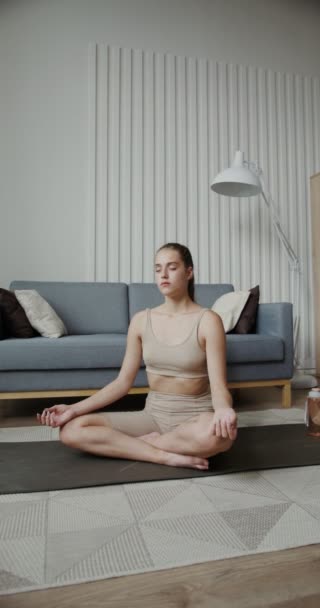 Chica europea en ropa deportiva se sienta en una posición de loto con los ojos cerrados — Vídeos de Stock