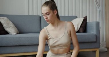 Spor giyimli Avrupalı bir kız Lotus pozisyonunda oturan bir dizüstü bilgisayar kullanıyor