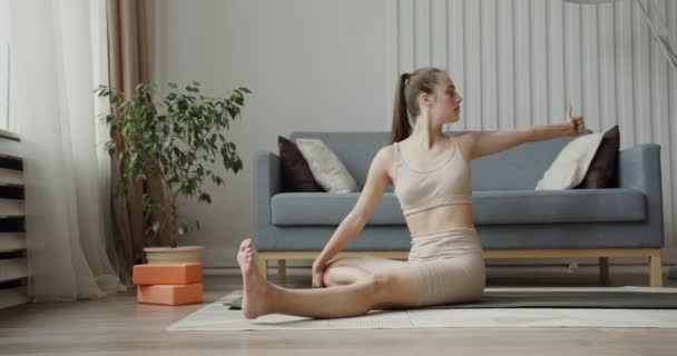 Ragazza europea vestita in abbigliamento sportivo, facendo esercizi seduti su un tappeto da ginnastica — Video Stock