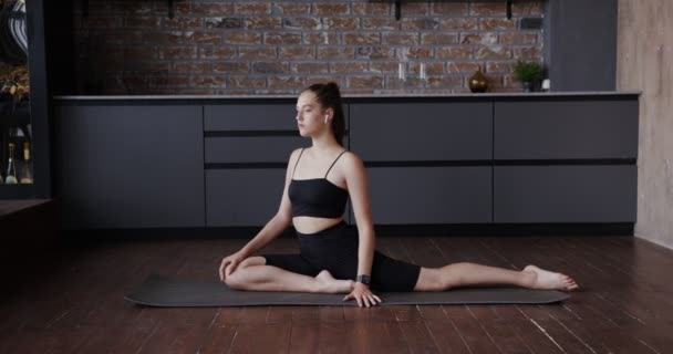 Chica europea vestida con ropa deportiva se extiende sobre una alfombra de gimnasia — Vídeos de Stock