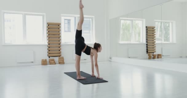 Європейська дівчина, одягнена в спортивний одяг, займається гімнастичними вправами в спортзалі. — стокове відео