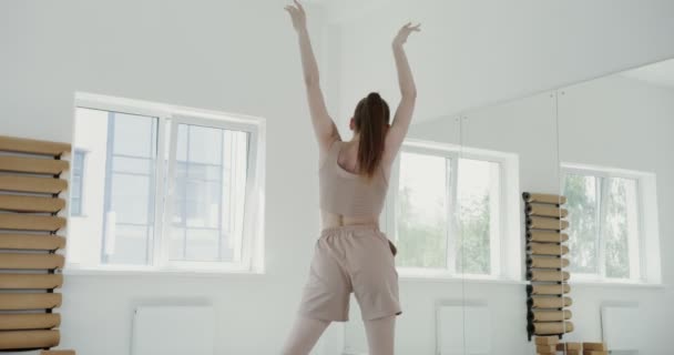 Європейська дівчина з спортивного одягу робить ритмічні балетні прогулянки. — стокове відео