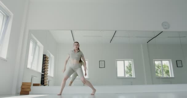 Ragazza europea in abbigliamento sportivo fare balletto ritmico affonda e salta — Video Stock