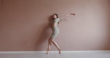 Spor giyinen Avrupalı bir kız duvarın yanında jimnastik yapıyor.