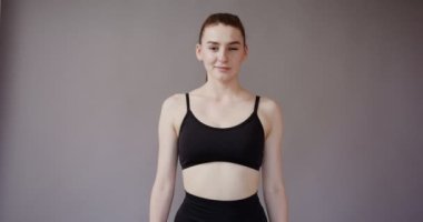 Spor giyinen Avrupalı bir kız kameraya bakıp gülümsüyor.