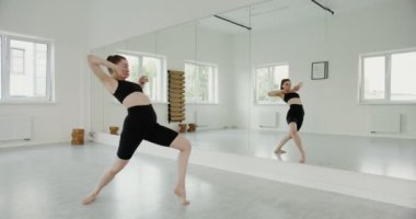 Açık tenli bir kız aynanın önünde ritmik bir şekilde dans eder.