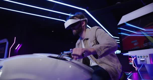 En man med skägg i virtual reality glasögon styr en motorcykel. — Stockvideo