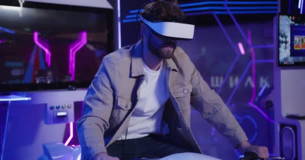 Un hombre con barba en gafas de realidad virtual controla una motocicleta. — Vídeos de Stock