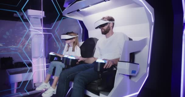 Un homme et une fille portant des lunettes de réalité virtuelle sur une attraction 5D — Video