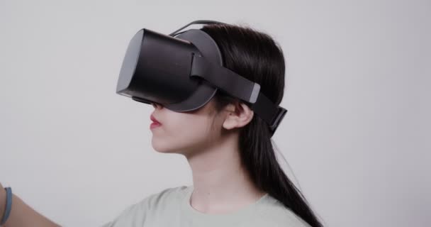 Asian girl in virtual reality glasses with joysticks plays in a 5D attraction — Stock Video