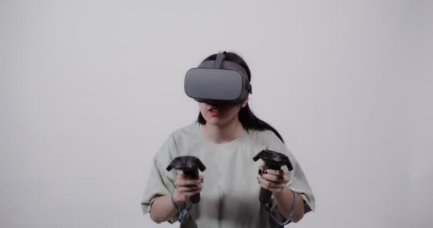 Asian girl in virtual reality glasses with joysticks plays in a 5D attraction — Stock Video