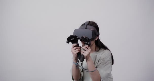 Asian girl in virtual reality glasses with joysticks plays in a 5D attraction — Stock Video