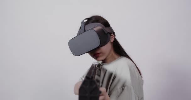 Asian girl in virtual reality glasses with toy weapon plays in a 5D attraction — Stock Video