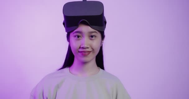 Menina de aparência asiática em óculos de realidade virtual sorrindo enquanto a câmera — Vídeo de Stock