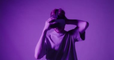 Kızıl saçlı adam ciddi ciddi kameraya bakıyor ve sanal gerçeklik gözlüğü takıyor.