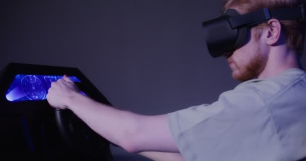 En rödhårig kille i virtuella verklighetsglasögon styr simulatorn i 5D — Stockvideo