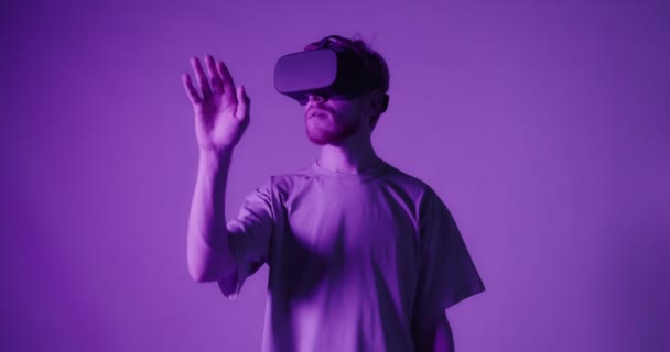 Um cara ruivo usando óculos de realidade virtual move a cabeça e as mãos — Vídeo de Stock