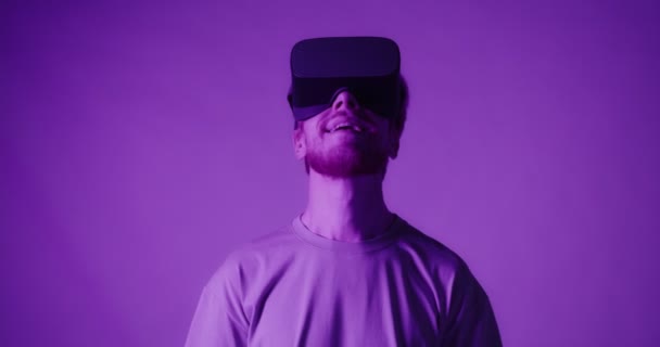 A red-haired guy wearing virtual reality glasses moves his head — Stock Video