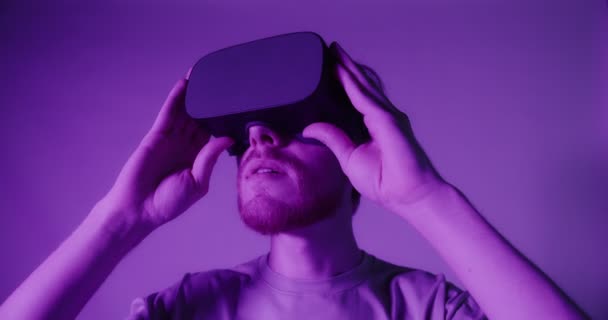 Um cara ruivo em óculos de realidade virtual move a cabeça e fica surpreso — Vídeo de Stock