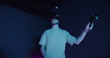 Elinde joysticklerle sanal gerçeklik gözlüğü takan bir adam.