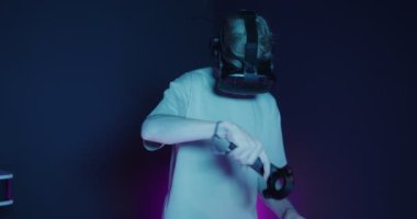 Elinde joysticklerle sanal gerçeklik gözlüğü takan bir adam.