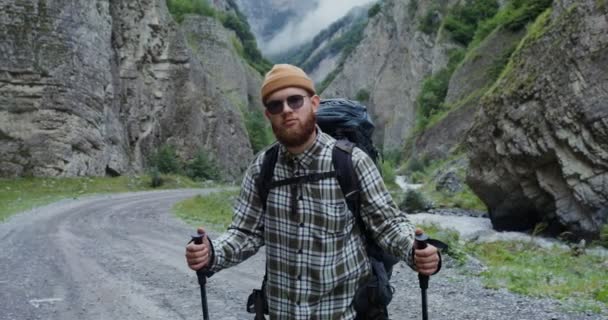 Ein junger Mann steht mit Stöcken für sportliche Spaziergänge zwischen den Felsen. Der Kaukasus — Stockvideo