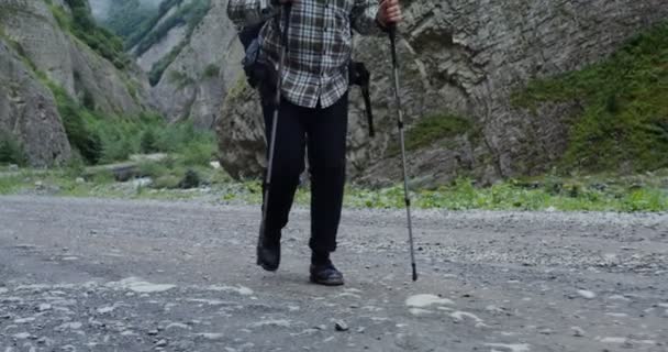 岩の間をスポーツ用の棒で歩く男。コーカサス地方 — ストック動画