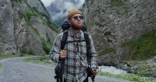 Un joven camina con palos para hacer deporte caminando entre las rocas. El Cáucaso — Vídeo de stock