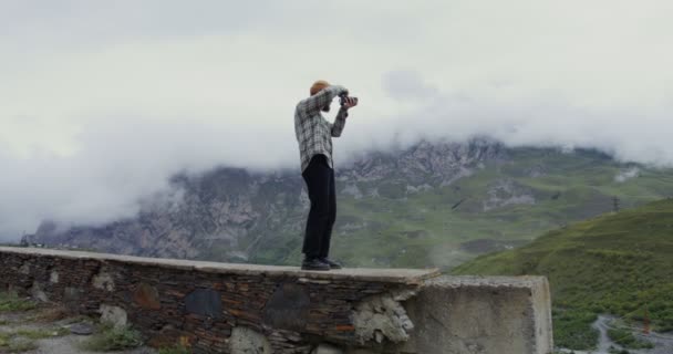 Rusya, Kafkasya. Bir adam kamerayla dağların fotoğraflarını çekiyor. — Stok video