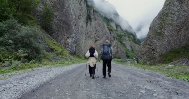 Russia, Caucaso. Una giovane coppia di turisti cammina lungo la strada tra le rocce — Video Stock