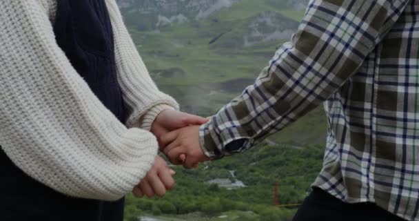 Um jovem casal de pé de mãos dadas contra montanhas verdes close-up — Vídeo de Stock