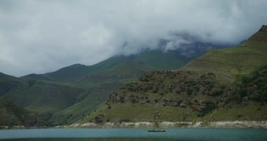 Bir kız, dağ gölünde sandalda oturan bir adamın fotoğrafını çekiyor.