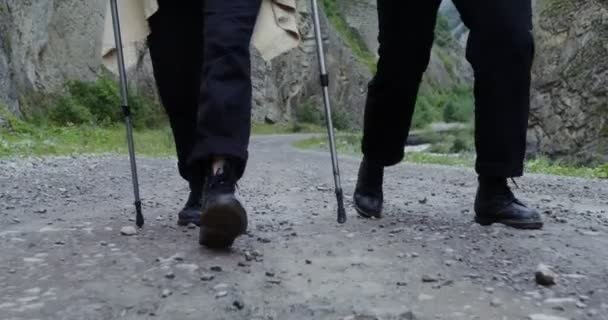 Ein Touristenpaar läuft die Straße entlang zwischen den Felsen. Beinahe-Nahaufnahme — Stockvideo