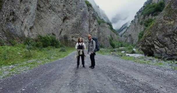 Il Caucaso. Una coppia di escursionisti si trova sulla strada tra le rocce e guarda la macchina fotografica — Video Stock