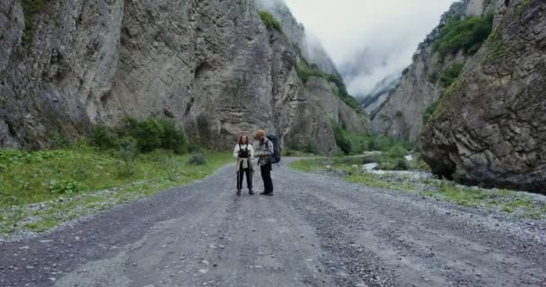 Kaukasus. Ett par vandrare står på vägen bland stenar och tittar på kameran — Stockvideo