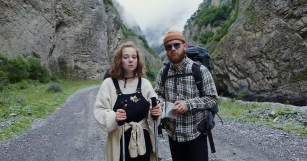 Der Kaukasus. Ein paar Wanderer stehen auf der Straße zwischen Felsen und blicken in die Kamera — Stockvideo