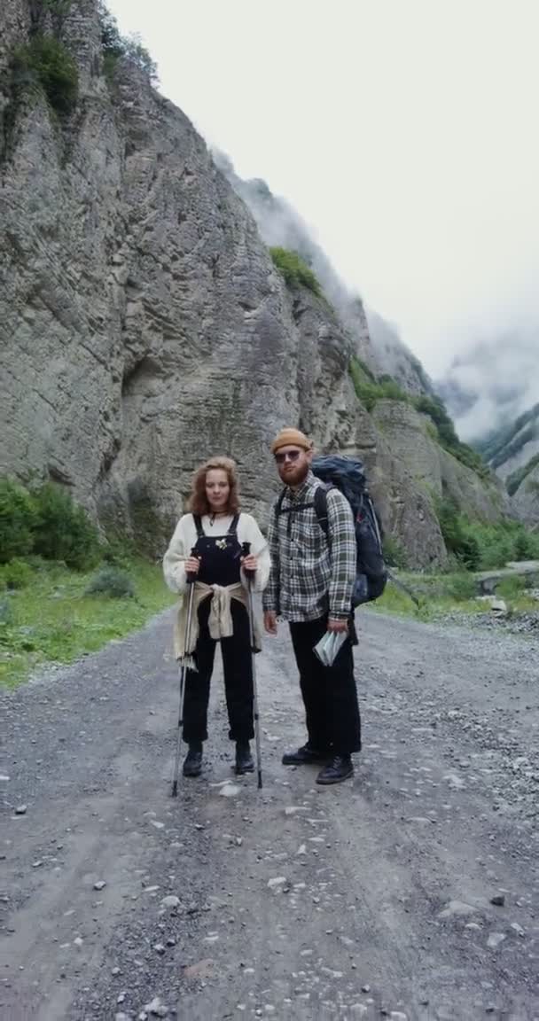 Kaukasus. Ett par vandrare står på vägen bland stenar och tittar på kameran — Stockvideo