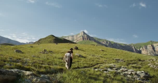 Rusland, Kaukasus. Een jong stel klimt een groene heuvel op, hand in hand. — Stockvideo
