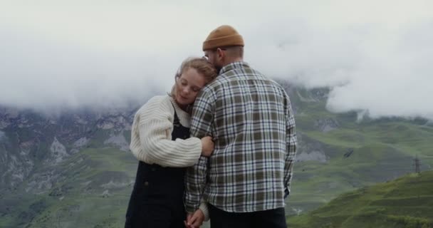 Un jeune couple s'étreint et se tient la main sur fond de montagnes — Video