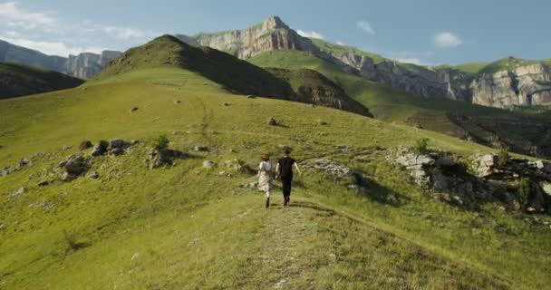 Rusko, Kavkaz. Mladý pár vyběhl na zelený kopec a držel se za ruce — Stock video