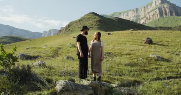 Rússia, Cáucaso. Um jovem casal de mãos dadas e olhando um para o outro na colina — Vídeo de Stock