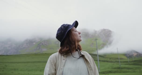 Kaukázus, Elbrus. Egy fiatal nő körülnéz, miközben a hegyek között áll. — Stock videók