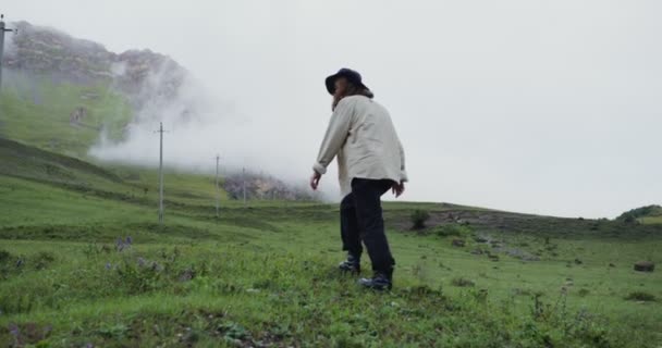 Kaukasus, Elbrus. En ung kvinna går upp för berget och ser tillbaka. — Stockvideo