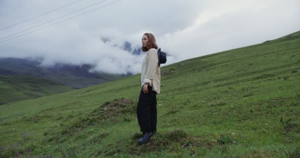 Kaukázus, Elbrus. Egy fiatal nő nézi a kamerát a hegyek között. — Stock videók