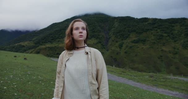 Кавказ, Ельбрус. Молода жінка оглядається навколо, стоячи серед гір. — стокове відео